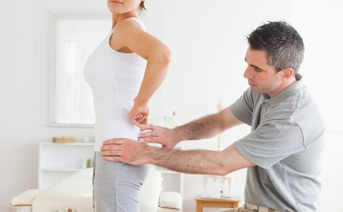Chiropractor examining a charming woman's back in a room